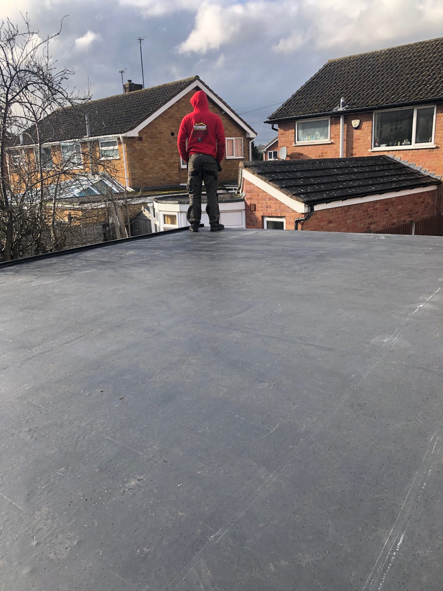 A team member standing on the corner of a freshly finished flat roofing job