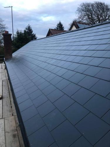 A roof of shiny new grey slates that have been laid