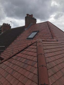 An image showing a new roofing job of red tiles with a built in velux window