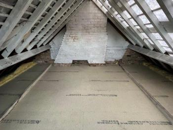 Attic with white walls and white supporting beams being installed and insulation 